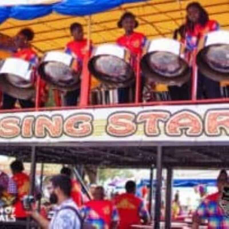 A steel drum band plays on a colorful stage labeled 